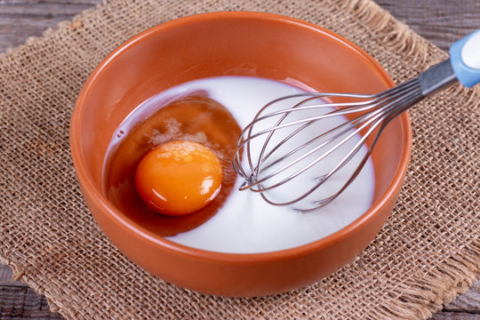 Egg with milk in a deep bowl with a whisk