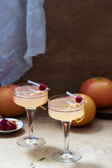 Champagne cocktail with grapefruit juice, garnished with zest and raspberries. Rustic style.