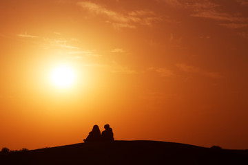 Desert nomads on the crest of a barchan at sunset