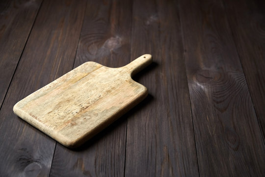 Empty clean handle cutting board on brown wooden background with copy space