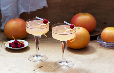Champagne cocktail with grapefruit juice, garnished with zest and raspberries. Rustic style.