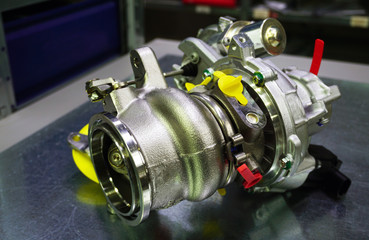 Modern turbocharger on a steel background. Turbocharger element allows you to significantly...