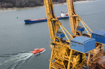 SEAPORT - Cranes reloading on the quay and a ship sailing by water in Swinoujscie