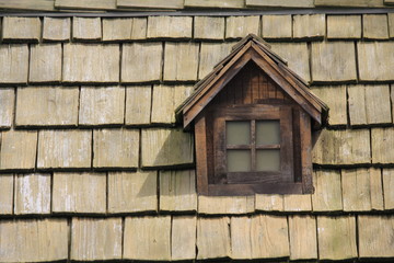 Fototapeta na wymiar old window on the roof of cedar shingles