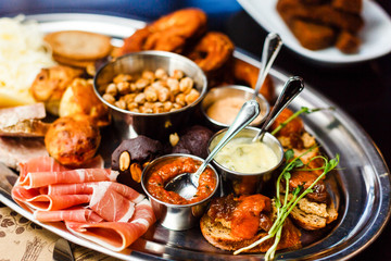 Spanish cuisine concept. Slices of jamon, chorizo, sausage. Bowls with sauce. Bruschetta with sauce. Italian antipasti. European gourmet mix