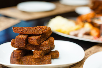 Pile of rye bread toasted sticks on a white plate. Appetizers, snacks on buffet table