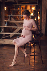 Pregnant happy Woman touching her belly. Pregnant middle aged mother portrait, caressing her belly and smiling close-up. Healthy Pregnancy concept, brunette expectant female on blue background