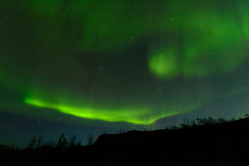 Fototapeta na wymiar Aurora borealis over the hills. At night in the sky in the north.