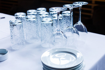 Empty glasses for wine, water, beer, drinks on white table. Glasses turned upside down. Arrangement for reception, ceremony in restaurant
