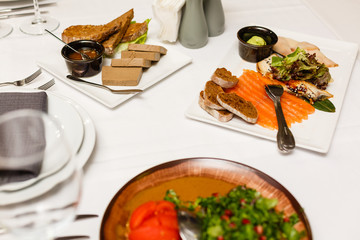 Fish platter, meat platter, sauce, and bread in restaurant. Sliced fish fillet on a white plate. Meat snacks