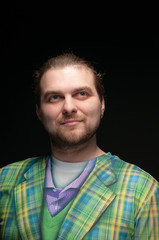 handsome stylish bearded man in green elegance plaid coat looking away isolated on black