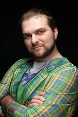 handsome confident bearded man with stylish hair in green elegance checkered coat crossed arms and looking at camera isolated on black