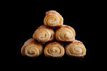 Home bakery. Cottage cheese cookies on a black background folded in a pyramid. Biscuits with sugar is in the form of a roll.