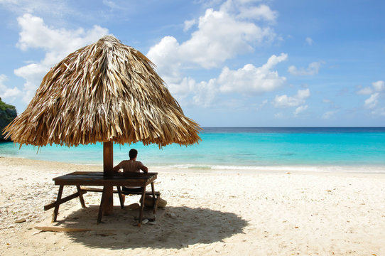 Curacao &ndash; Caribbean beach &ndash; Man relaxing on shadow &ndash; blue sea &ndash; Kenepa Chiki beach