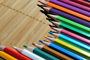 Fototapeta premium multicolored pencils laid out by an arc on a straw background.
