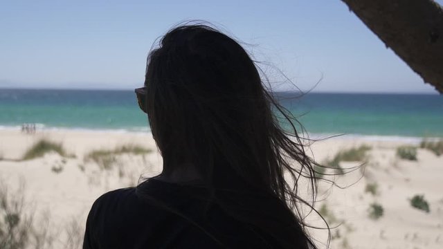 Mujer pensativa observando la playa de arena blanca HD 
