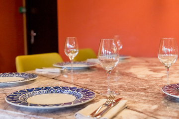 Glasses, forks, knives, plates on a table in restaurant served for dinner.catering services background with glasses of wine in restaurant.Empty glasses.table setting,restaurant serving, interior.
