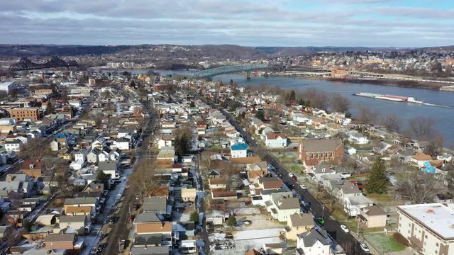 A slowly moving forward winter aerial establishing wide shot of the shoreline of Monaca, Pennsylvania with a coal barge on the Ohio River in the distance. Pittsburgh suburbs.  	