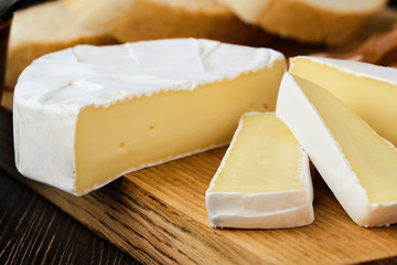 Close up of camembert or brie cheese on wooden cutting board (macro photo with shallow depth of...