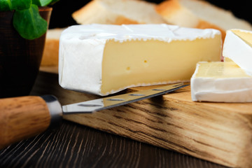 Close up of camembert or brie cheese on wooden cutting board (macro photo with shallow depth of field)