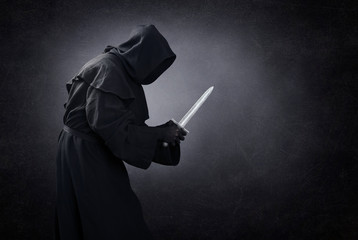 Hooded man with dagger in the dark