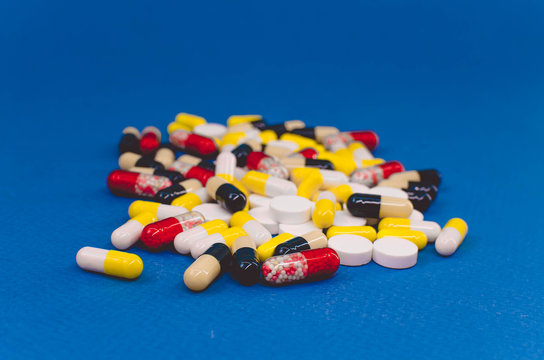 heap of pills of different colors on a blue background