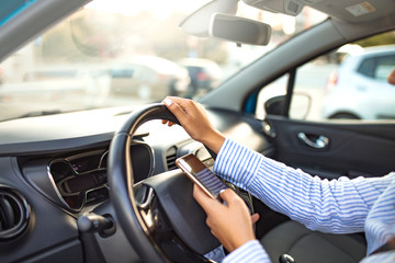 Mockup of woman using phone while driving behind the wheel. Closeup inside vehicle of hand holding...