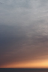 Obraz premium Sun behind clouds above sea skyline. Beautiful orange sky over horizon at sunset. Lonely peaceful feeling.