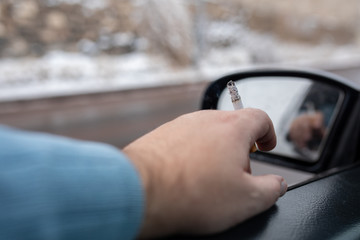 Driver with a cigarette in hands. Smoking while driving a car. Smoking cigarette in car