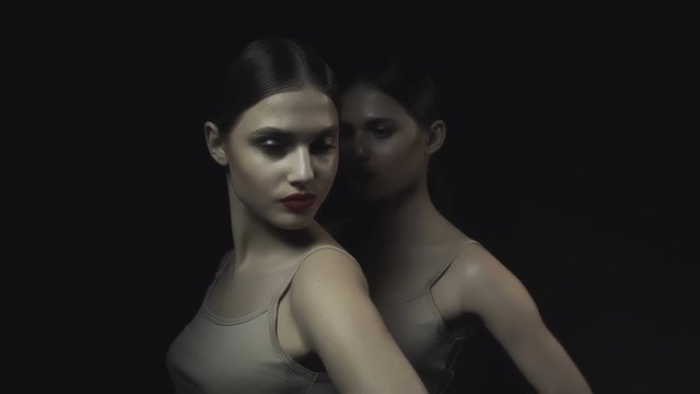 Girls in the dark. Two twin sisters on a dark background. Red lipstick. Perfect skin. Nude makeup.