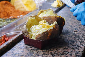 Die Vorbereitung von einem Kumpir mit K&auml;se und Butter 