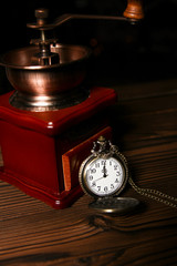 a pocket watch with a coffee grinder on a wooden background