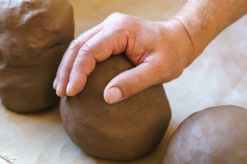 Male hand and piece of pottery clay.
