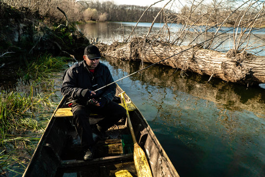 A men fishing on river from his wooden boat
