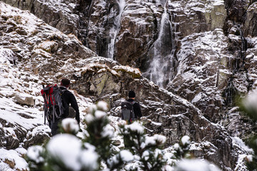 Turystyka piesza. Turyści idą po skalistym zboczu obok wodospadu w Tatrach. Siklawa wodospad. Polska. Treking po skałach. 