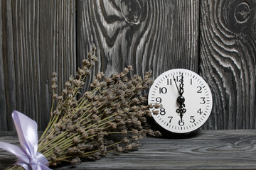 A bouquet of lavender on a background of brushed boards. Hearts cut out of paper and watches.