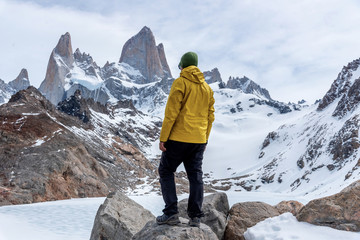 A hiker with a yellow jacket on the base of Fitz Roy Mountain in Patagonia, Argentina