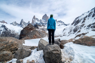 A hiker woman with a blue jacket on the base of Fitz Roy Mountain in Patagonia, Argentina