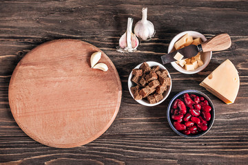 Healthy food: healthy food source against a wooden background. Ingredients for cooking: red beans, hard cheese, crackers, brown bread, garlic. Copy space. Place for text on a cutting board.
