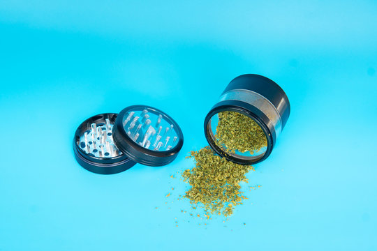 Close up of cannabis - marijuana buds, leaf and accessories - grinder, rolling papers and rolled joint - splif. on blue Background