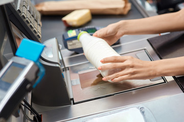 Young adult woman cashier checking price on checkout