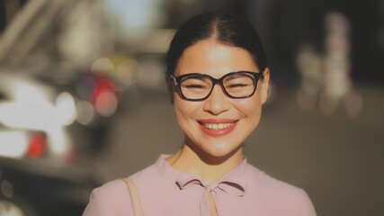 A brunet middle-aged businesswoman in glasses happily laughing in sunny day