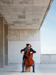 beautiful girl plays the cello with passion in a concrete environment © PHOTOGENIA STOCK