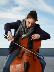 beautiful girl plays the cello with passion in a concrete environment