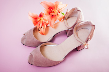 Obraz na płótnie Canvas Female pink shoes with lily flowers on pink background. Stylish suede footwear. Women fashion