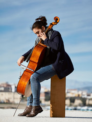 beautiful girl plays the cello with passion in a concrete environment