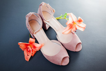 Female pink shoes with lily flowers on grey background. Stylish suede footwear. Women fashion