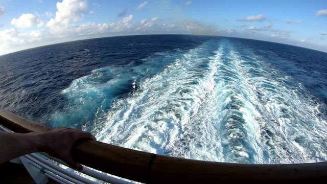 First person view of a man watching Caribbean Sea from the aft of a cruise ship