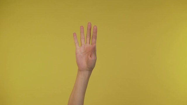 Woman hands showing peace gestures over yellow background 4K