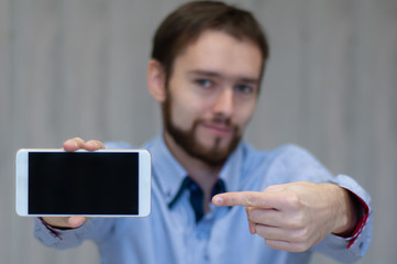 Business man holds and shows mobile phone. Bearded man in suit showing smart phone with blank...